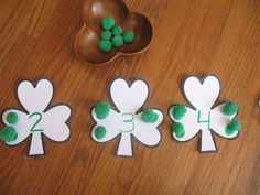 four shamrock shaped cut outs sitting on top of a wooden table next to a bowl