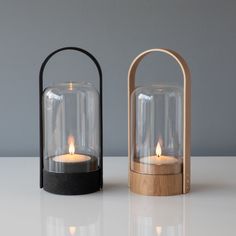 two wooden and glass candle holders on a table