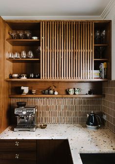 a coffee maker is on the counter in this small kitchen with wooden cabinets and shelves