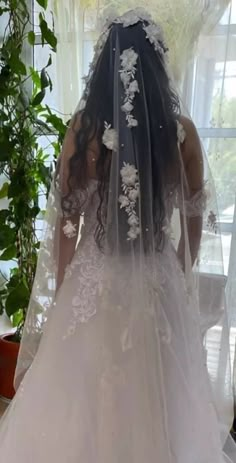 the back of a bride's wedding dress in front of a window with greenery