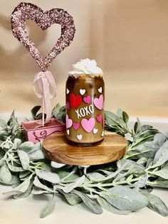 a mason jar sitting on top of a wooden table next to some leaves and hearts