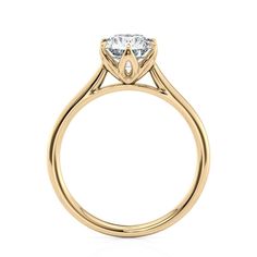 a yellow gold engagement ring with a single diamond in the center, on a white background