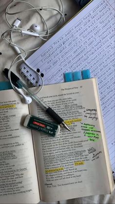 an open book with earbuds and headphones on it next to some books