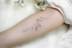 a woman's arm with flowers and the word love written in cursive writing