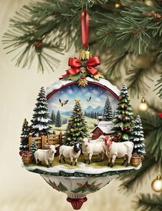 a christmas ornament hanging from a tree decorated with sheep and trees in the snow