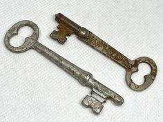 two old keys sitting on top of a white cloth covered table next to each other