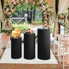 three black speakers are sitting in front of an arch with flowers and fruit on it