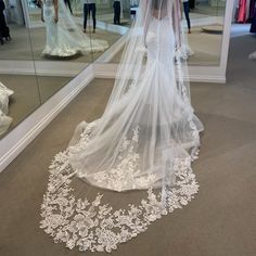 a woman in a wedding dress looking at herself in the mirror while wearing a veil