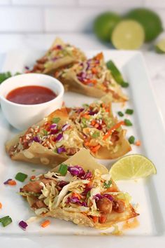 three pieces of flatbread with coleslaw and lime on a white plate next to a small bowl of dipping sauce