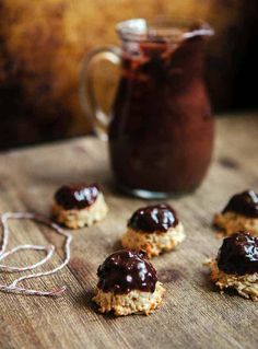 chocolate covered cookies sitting on top of a wooden table next to a jar of chocolate