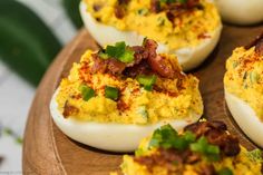 deviled eggs with bacon and chives on a wooden platter, ready to be eaten