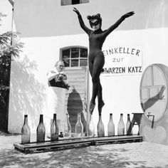 an old black and white photo of a man in a diving suit standing next to bottles