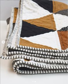 a close up of a quilt on top of a white table with black and brown stripes