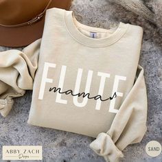 Show your marching band spirit with this flute mama crewneck sweatshirt. We print on warm and cozy Gildan brand sweatshirts. Need a different mom name or spelling? Message us before ordering to request custom edits! More band and orchestra instrument shirts available at my homepage https://www.etsy.com/shop/AbbyZachDesigns ----HOW OUR SHIRTS ARE MADE ----  * We use the process of DTG, which stands for direct to garment printing. We partner with a professional printer who applies ink directly int Marching Band Mom, Neutral Minimalist, Mom Sweater, Band Shirts, Mama Sweatshirt, Branded Sweatshirts, Mom Sweatshirt, Marching Band