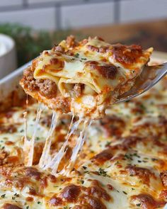 a close up of a casserole with cheese being lifted from the casserole