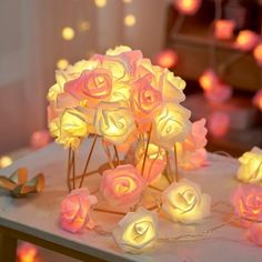 a bunch of fake roses sitting on top of a table next to some string lights