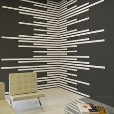 a chair sitting in front of a black wall with white strips painted on it's walls