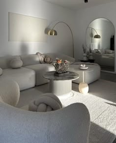 a living room filled with white furniture and lots of sunlight coming in through the windows