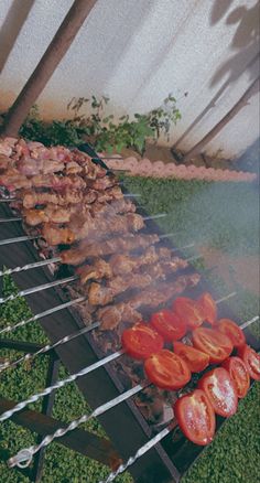 several skewers with meat and tomatoes cooking on them in an outdoor bbq