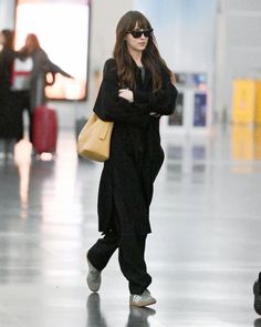 a woman walking through an airport carrying a yellow bag