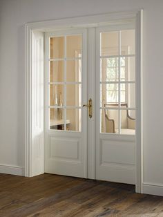 an empty room with two white doors and wood flooring in front of the door