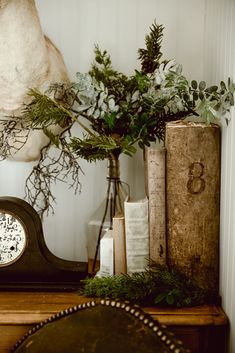 a clock sitting on top of a wooden table next to a vase filled with flowers