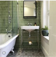 a bathroom with green tiles and a white bathtub next to a sink under a mirror