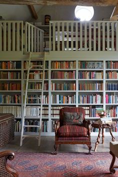 a living room filled with lots of books on top of a book shelf next to a ladder