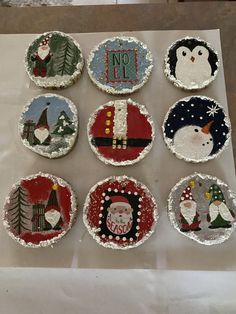 twelve decorated christmas cupcakes sitting on top of a white paper bag with frosting