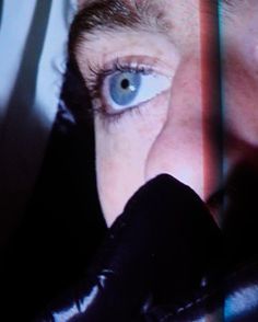 a woman with blue eyes looking at something on the screen in front of her face