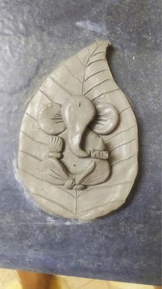 a clay carving of an elephant holding a baby in it's trunk on a piece of wood