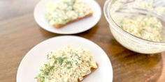 two white plates topped with food on top of a wooden table