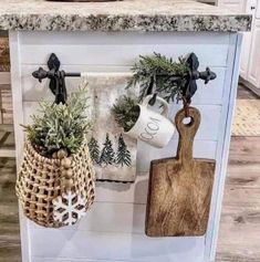 two potted plants are hanging from hooks on the wall next to a cutting board