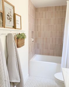 a bathroom with a toilet, bathtub and towels hanging on the wall next to it