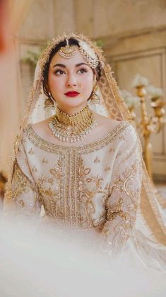 a woman in a wedding dress wearing a gold and white outfit with jewelry on her head