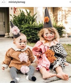 two dolls sitting next to each other in front of a house with halloween decorations on their heads