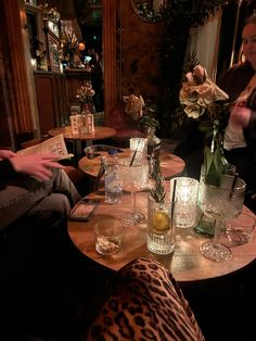 people sitting at a table with glasses and bottles on it in a dimly lit room