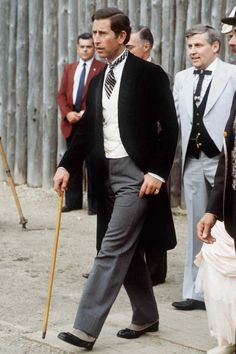 a man in a suit and tie walking down the street with other men behind him