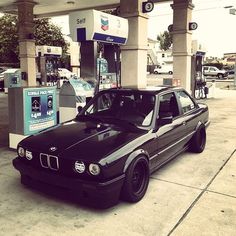 a black car parked in front of a gas station