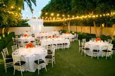 tables and chairs are set up for an outdoor event with string lights strung over them