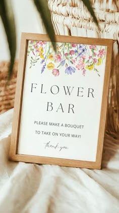 a flower bar sign sitting on top of a bed next to a wicker basket