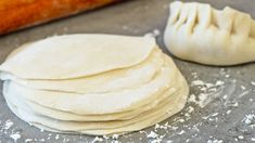 a stack of uncooked pizza dough sitting on top of a table next to a loaf of bread