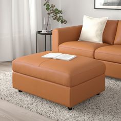 an orange leather couch and ottoman in a living room with white carpeted flooring