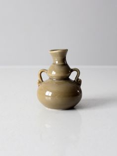 a brown vase sitting on top of a white table