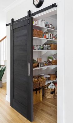 an open pantry door with baskets and other items in the shelves next to it on a wooden floor