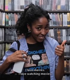 a woman holding a book in front of a bookshelf filled with dvds and movies