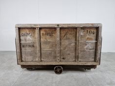 an old wooden box with some writing on the side and wheels in front of it