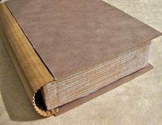 an open brown book sitting on top of a white floor next to a red object