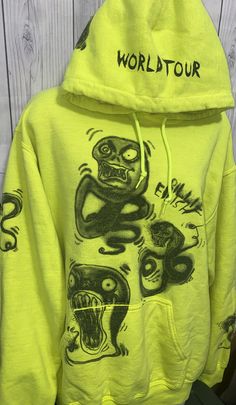 a yellow hoodie with an image of monsters and words on the front, which says world tour