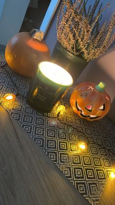 two lighted pumpkins sitting next to each other on a wooden floor near a potted plant